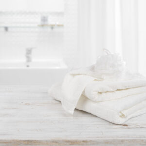 Fluffy towels and wisp of bast over blurred bathroom background