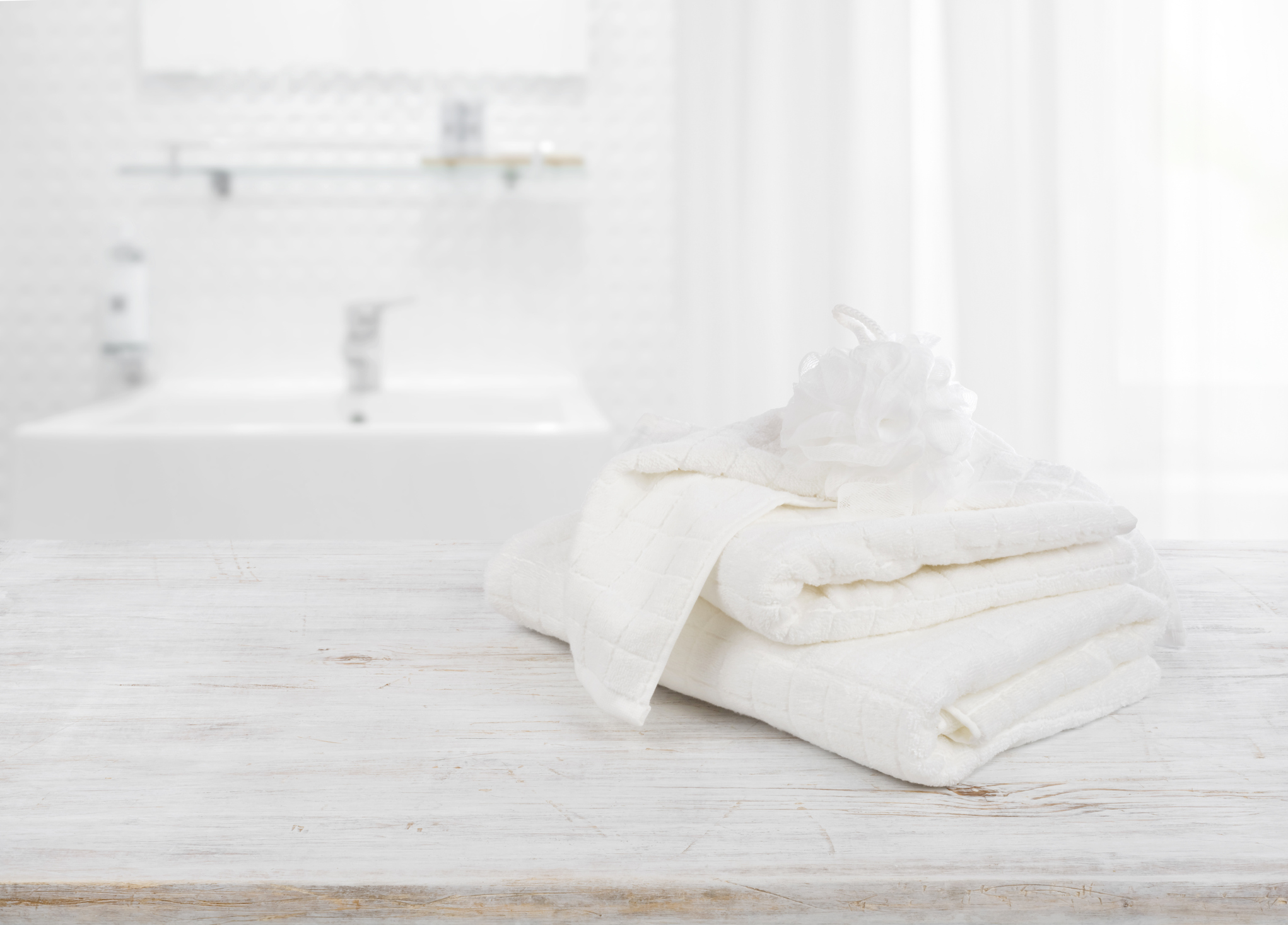 Fluffy towels and wisp of bast over blurred bathroom background