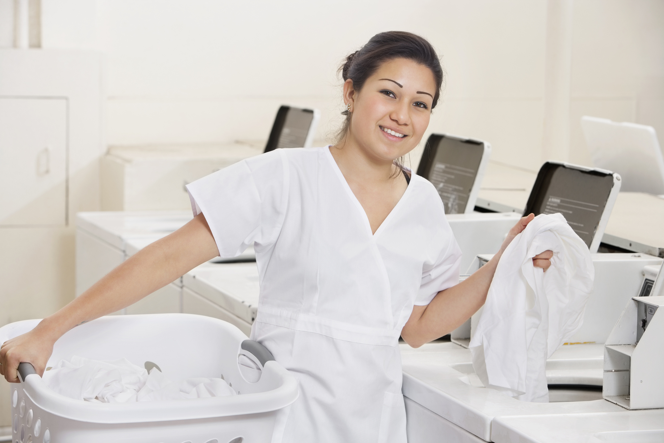 happy young employee putting clothes in washing machine